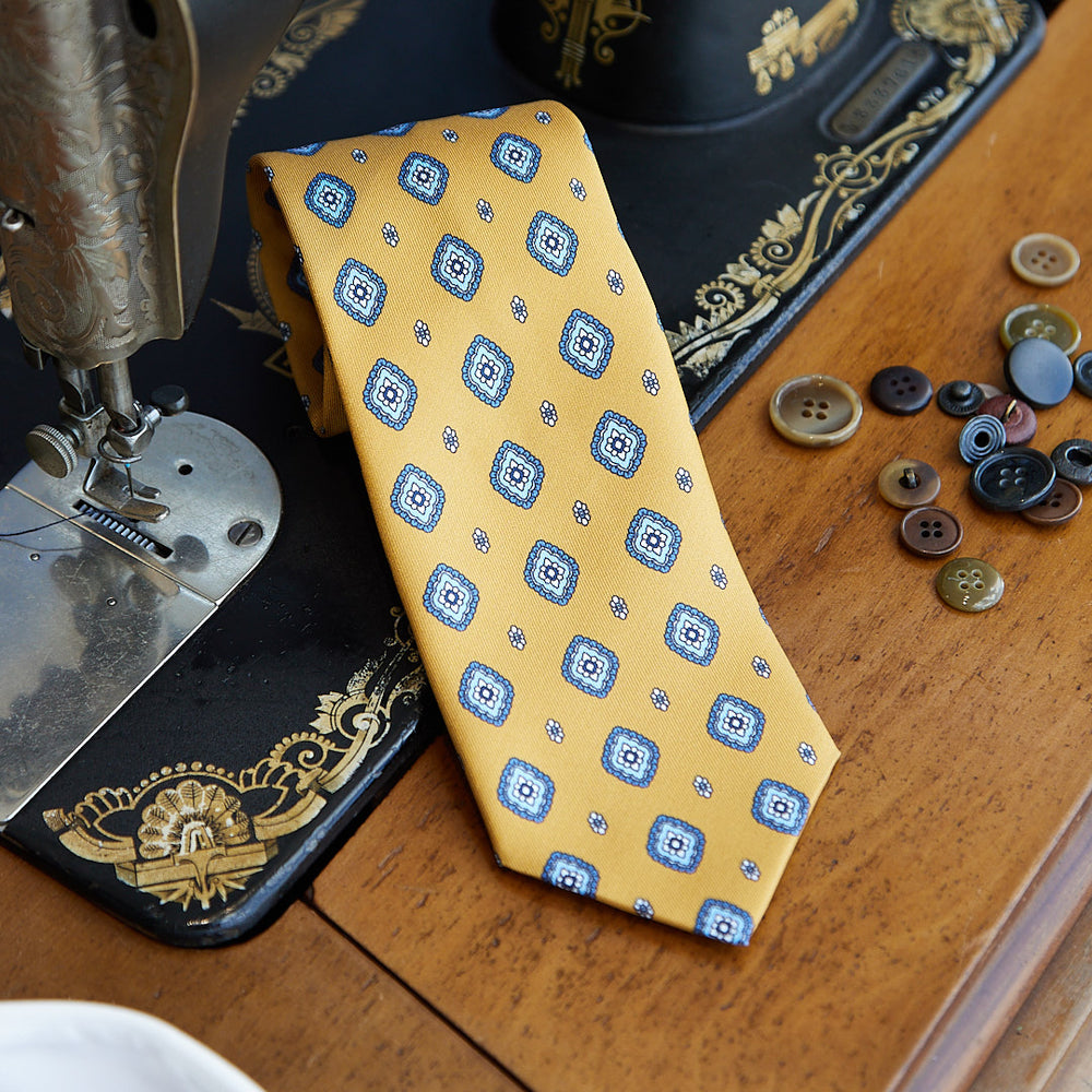 Cravatta fantasia in pura seta senape con disegno azzurro e bianco
